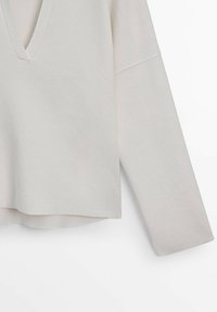 T-shirt gris clair à col en V et manches longues, fabriqué dans un tissu doux avec une coupe décontractée. Comprend des épaules tombantes et un ourlet légèrement arrondi.