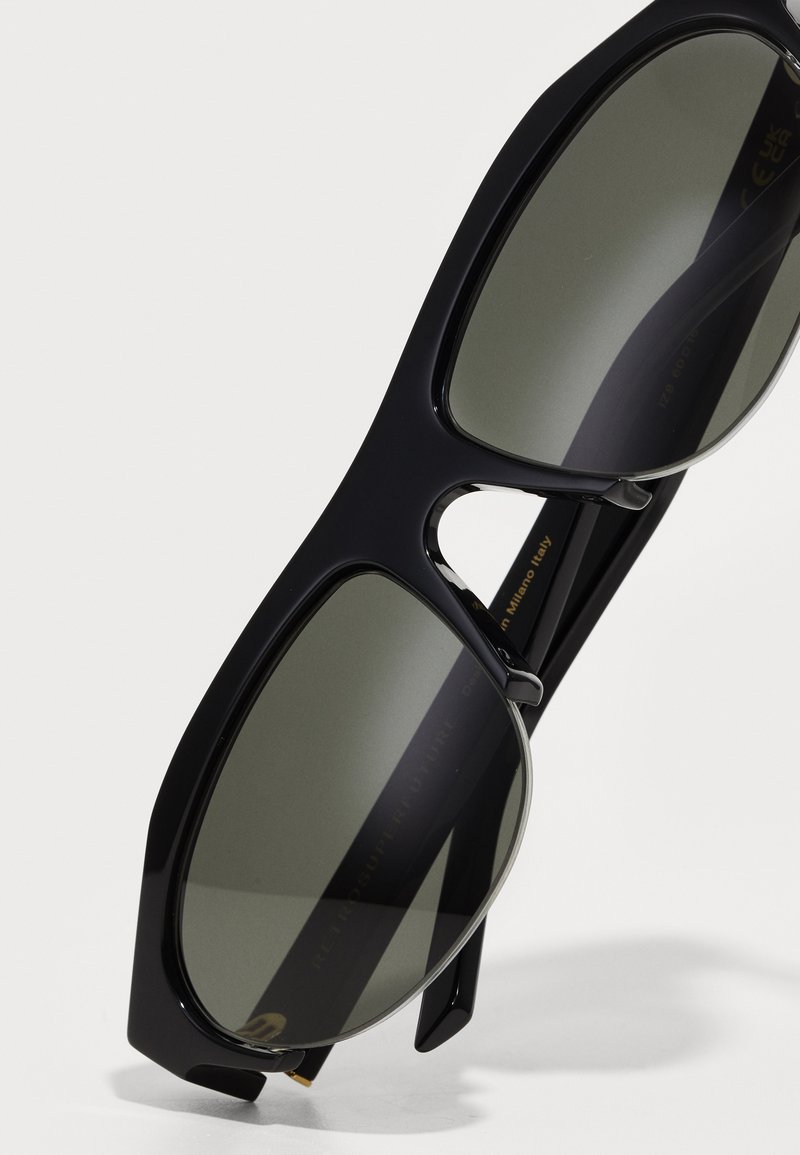 Zwarte oversized zonnebril met donkergetinte lenzen, een chunky rechthoekig montuur en subtiele zilveren accenten. Gemaakt van lichtgewicht kunststof.