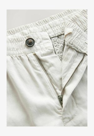 Vaaleat shortsit, joissa on joustava vyötärö, vetoketjusauma ja nappisulku. Sisävuori on vähäisellä kukkakuviolla.