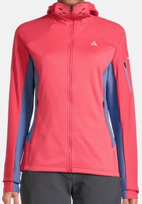 Chaqueta softshell rosa y azul con un diseño ajustado, bolsillos con cremallera, un cuello alto y paneles texturizados en los hombros.