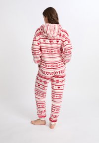 Rot-weiß gemusterter Overall mit Kapuze, verziert mit festlichen Motiven wie Herzen und Schneeflocken, aus weichem, plüschigem Stoff gefertigt.