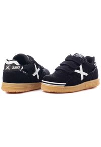 Zapatillas de ante negro con detalles en blanco y correas de Velcro. Cuenta con una suela de goma y un detalle del logo en el talón y la lengüeta.