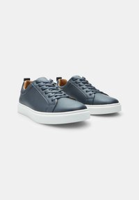 Marineblaue Ledersneaker mit weißen Gummisohlen, runder Zehenform, sechslöchrigem Schnürsystem und kontrastierender Innenauskleidung. Mit einer kleinen Fersenschlaufe.