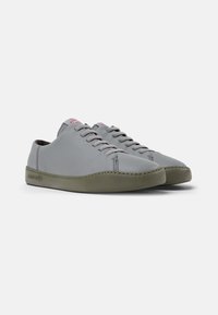 Sneakers in pelle grigia con profilo basso, suola in gomma verde e lacci grigi coordinati. Presentano cuciture sottili e un logo discreto sulla linguetta.