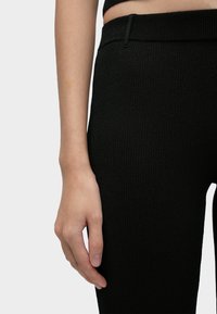 Čierne žebrované legíny s vysokým pásom, vyrobené z mäkkého materiálu. Majú priliehavý strih a hladkú textúru, ktoré zdôrazňujú pohodlie.