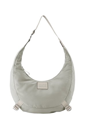Hellgraue, halbmondförmige Schultertasche mit verstellbarem Riemen und vorderem Etikett mit der Aufschrift "Studio Berlin" auf einfarbigem Hintergrund.