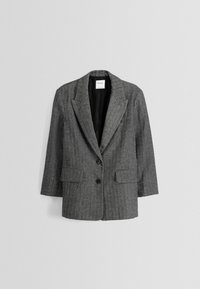 Blazer grigio a quadri con rever a punta, due tasche anteriori, due bottoni neri e una fodera interna liscia. Vestibilità sartoriale, maniche di lunghezza intermedia.