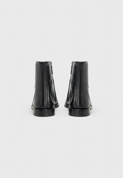 Μαύρα δερμάτινα μποτάκια αστραγάλου με λεία υφή, στρογγυλεμένη μύτη και κλείσιμο με φερμουάρ στο πίσω μέρος, με χαμηλή, επίπεδη σόλα.