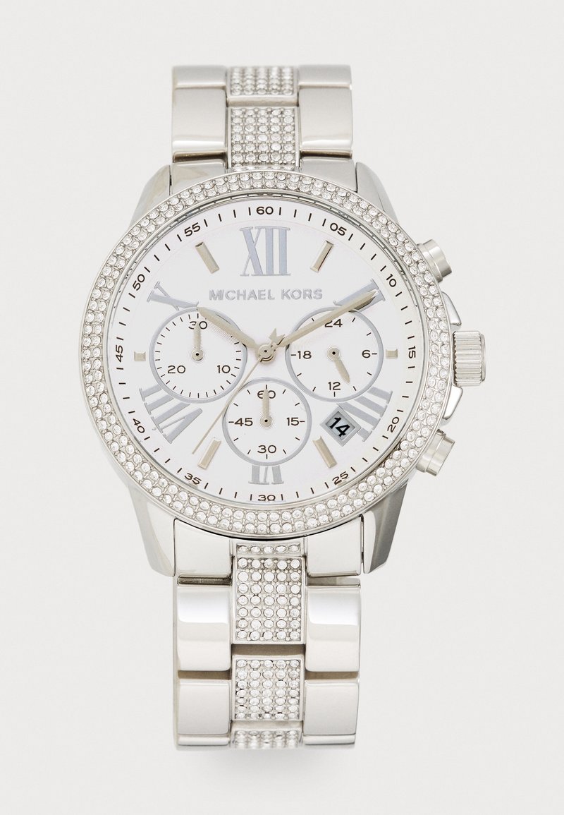 Montre-bracelet Michael Kors argentée avec lunette et bracelet ornés de cristaux, cadran blanc, chiffres romains, trois sous-cadrans et affichage de la date à trois heures.