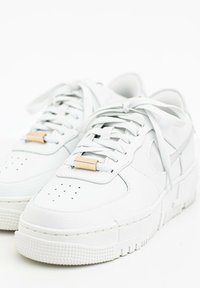 White leather sneakers with a textured finish, featuring a gold accent on the laces, perforated toe box, and a chunky white sole.