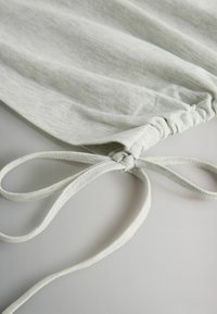 Világosszürke szövet enyhén texturált felülettel, összehúzott varrással és megkötött húzózsinór díszítő elemmel. Puha és rugalmas anyag.