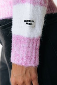 Pull en maille avec des rayures roses et blanches, tissu texturé, poignets côtelés, et une étiquette "Colourful Rebel" sur la manche gauche.