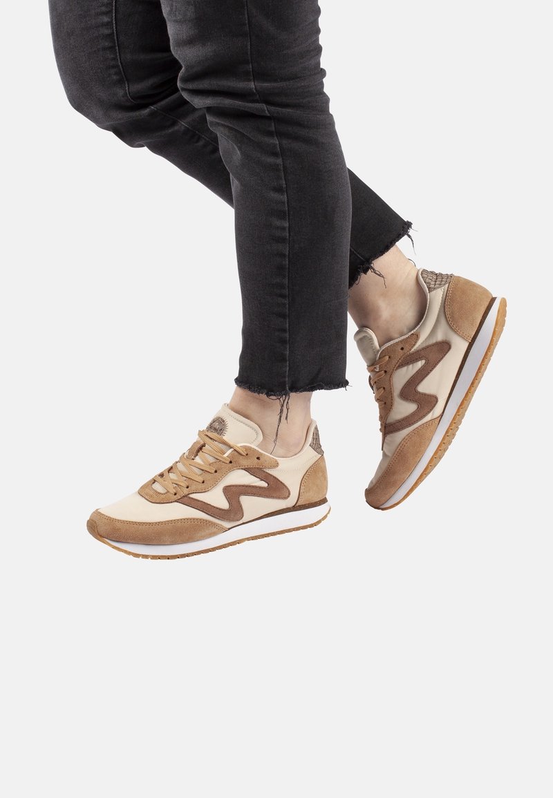 Sneaker beige e marroni in materiali scamosciati e in pelle. Presentano un design a onde, punta rotonda e dettagli testurizzati sul retro.