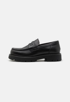 Black leather loafers with a rounded toe, textured accents on the front, and a chunky rubber sole with grooves for traction.