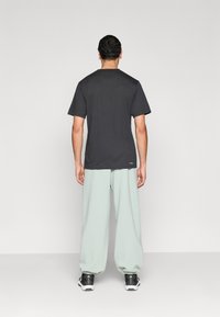 Μαύρο κοντομάνικο μπλουζάκι σε συνδυασμό με φαρδιά παντελόνια μέντας και μαύρα αθλητικά παπούτσια. Λείο βαμβακερό ύφασμα με άνετη εφαρμογή.