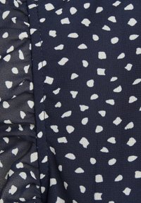 Navy fabric with white irregular spots, featuring a ruffled edge, smooth texture, and a lightweight, sheer finish.