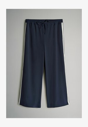 Jūras zila sporta bikses ar baltām sānu svītrām, elastīgu jostu un auklu. Brīvs piegriezums un viegls audums komfortam.