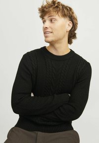 Schwarzer Strickpullover mit Zopfmuster, gerippten Bündchen und Saum sowie einem Rundhalsausschnitt, getragen von einer Person.