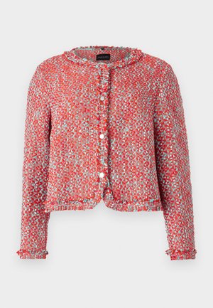 Veste tissée rouge et bleue avec un col arrondi, tissu texturé et coupe courte. Comprend des fermetures à boutons et des bords volantés.