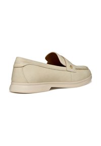 Μπεζ δερμάτινο παπούτσι χωρίς κορδόνια με στρογγυλεμένη μύτη, διακοσμητικές ραφές και λεπτομέρεια με χρυσό κουμπί. Επίπεδη μπεζ σόλα για άνεση.