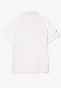 White short-sleeve polo shirt with a collar, "LACOSTE" text on right sleeve, and "ULTRA DRY" text near the bottom hem on the back.