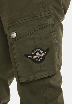 Pantalon cargo vert olive avec une poche à rabat fermée par un bouton en métal et un écusson Von Dutch représentant un crâne avec des ailes.