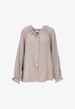 Blouse beige clair à manches longues avec boutonnage sur le devant, tissu texturé, col et poignets à volants avec détails en dentelle.