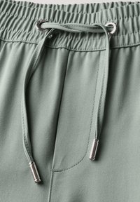 Ljusgröna joggers med en elastisk midja, som har ett snöre med silverdetaljer och strukturerad tyg.