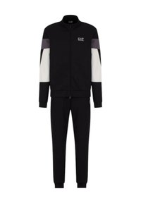 Tuta sportiva nera con giacca zip-up caratterizzata da pannelli bianchi e grigi. I pantaloni hanno un design affusolato con polsini elasticizzati.