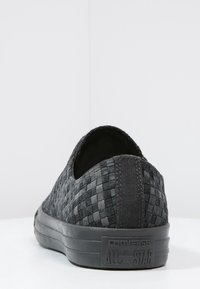 Černé pletené nazouvací boty s texturovaným svrškem, semišovými akcenty a gumovou podrážkou. Mají zaoblenou zadní část a embosované logo na patě.