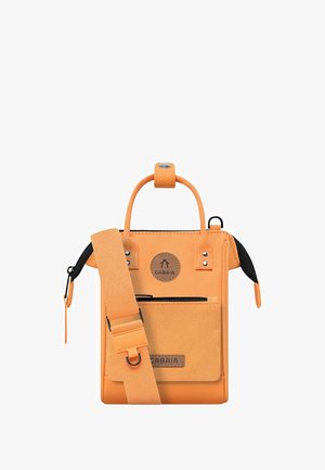 Orange fabric bag with a circular logo, zippered closure, front pocket, and adjustable strap. Features a sturdy handle and decorative studs.