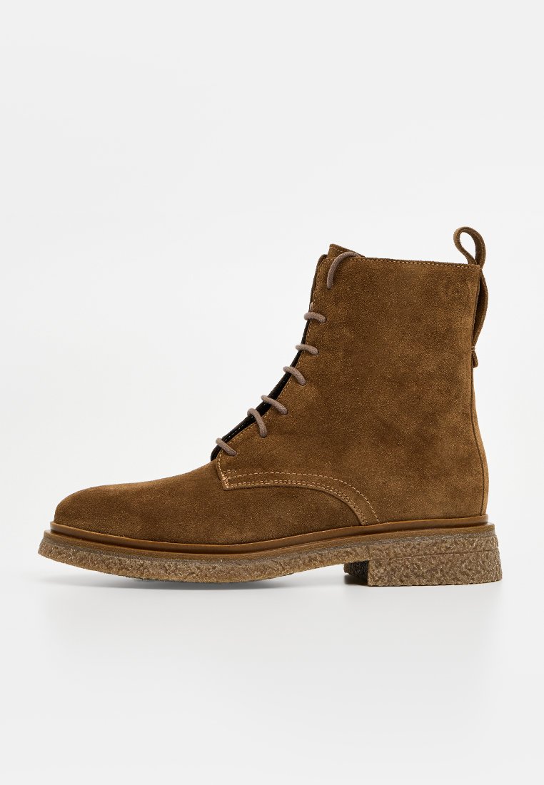Braune Wildleder-Schnürstiefelette mit strukturiertem Gummisohle und Zuglasche hinten, Seitenansicht vor weißem Hintergrund.
