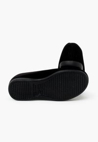 Scarpe nere flat con tomaia in tessuto morbido e suola in gomma liscia. La suola presenta un design testurizzato per una migliore aderenza. Realizzate in Spagna.