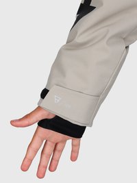 Mano con le dita tese che mostra la manica di una giacca beige con l'etichetta "10k" e un guanto da polso nero su uno sfondo semplice.