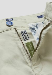 Lichtbeige broek met gestikte details, rits en een blauwe knop. Voorzien van geborduurde "M5" labels en een gestreepte binnenvoering.