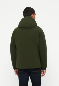 Giacca puffer verde con cappuccio, caratterizzata da una superficie liscia opaca e polsini elasticizzati, vista da dietro su uno sfondo uniforme.