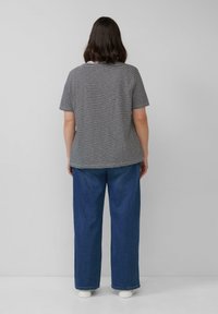 Gestreepte grijs en witte top met korte mouwen, gecombineerd met brede blauwe denim broek. De top heeft een ronde halslijn en een losse pasvorm.