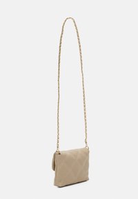 Borsa a tracolla trapuntata beige con catena. Presenta una cucitura a diamante e una texture morbida, con una forma rettangolare compatta.