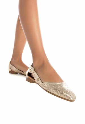 Bailarinas en beige metálico con un patrón geométrico en relieve, aseguradas con una correa de hebilla, y con una suela baja de goma marrón.