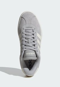 Sivi suede tenisice s bijelim detaljima, s zaobljenim vrhom, vezanjem na vezice i "adidas" logotipom na jeziku. Teksturirana gornja površina.