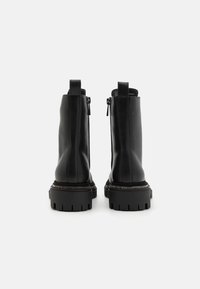 Black ankle boots made of smooth leather with a chunky rubber sole, featuring zippers and pull tabs for easy wear.