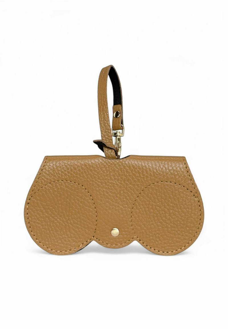 Pochette en cuir tan avec deux compartiments circulaires, texture lisse, fermeture à bouton-pression en métal, et une sangle pour le poignet. Présente un design minimaliste.