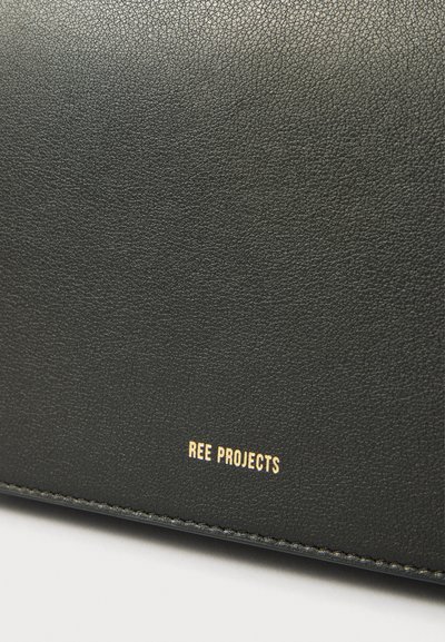 Crni kožni novčanik s teksturom i suptilnom zrnom, zlatni folijski logotip "REE PROJECTS" i vidljivo šivanje duž rubova.