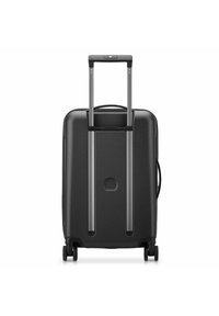 Valigia rigida nera con manico telescopico, doppie ruote e un esterno testurizzato. Presenta un logo circolare centrale sul retro.