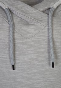 Jasnoszara bluza z kapturem o teksturowanym splotem, z plecionymi sznurkami i metalowymi końcówkami, podkreślająca swobodny design.