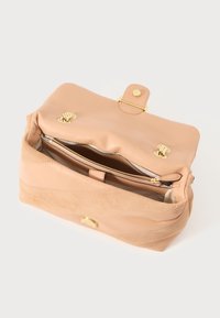 Borsa in pelle e suede color cuoio con chiusura a pattina, hardware dorato e una tasca con zip all'interno. Texture liscia e forma strutturata.