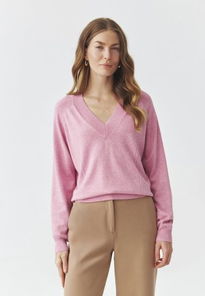 Lichtroze V-hals trui met lange mouwen, voorzien van ribgebreide manchetten en zoom. Zachte textuur, gecombineerd met beige op maat gemaakte broek.