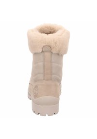 Botas de invierno de ante beige con un suave cuello de piel de fur, textura acolchada en el eje y una suela de goma sólida con surcos para tracción.