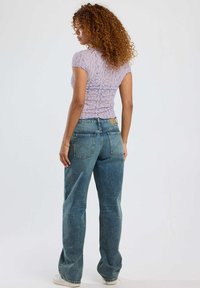 Light purple, fitted lace top with short sleeves paired with high-waisted, slightly loose blue jeans, featuring pockets and a textured finish.