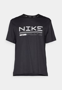 Fekete, rövid ujjú póló, könnyű anyagból készült. A pólón fehér "NIKS" felirat és Nike logó található, minimalista dizájn elemekkel.